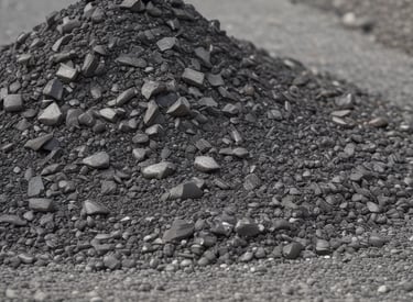 Stacks of crushed stone and bitumen drums ready for delivery at an industrial yard.