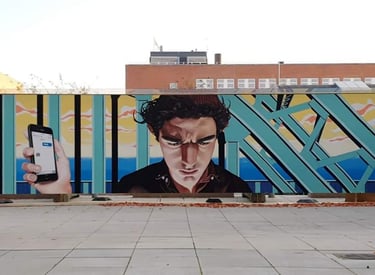 Urban street art mural depicting a man looking at a smartphone against a colorful geometric background.