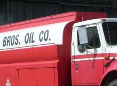 Red and white Fleming Bros. Oil Co. heating fuel delivery truck parked in front of a silo.