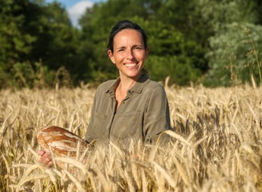 photo d'une boulangère tenant son pain dans un champ de blé