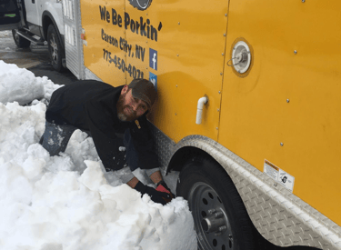 a man is laying on the snow in front of a truck