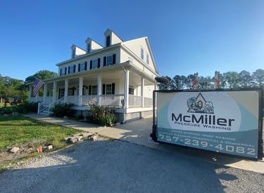 A McMiller Pressure Washing trailer parked in front of a clean white two-story residential home with a large porch.
