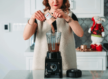 mujer preparando un batido usando una licuadora negra