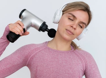 Mujer con camiseta deportiva rosa y audífonos usando un masajeador eléctrico