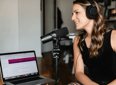 Mujer con audifonos y micrófono grabando un podcast