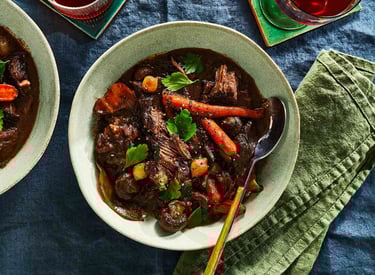 Hearty beef stew with carrots and potatoes simmering in Dutch oven.