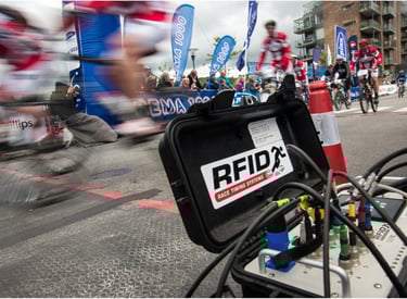 A picture of racers zooming by and RFID chip timing signal collector at a multi-sport event