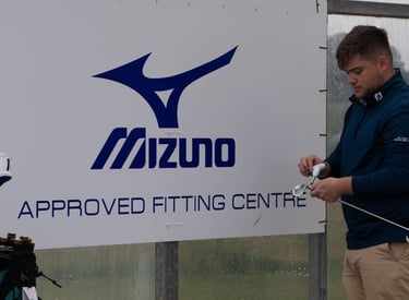 A golf coach in Aberdeen is adjusting a golf club during a custom fitting session for a client at an approved fitting centre