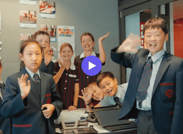 children in school uniforms waving to the camera