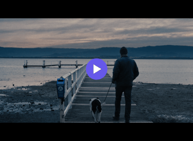 man and dog walking towards a jetty