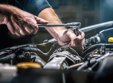 A mechanic using a wrench to work on a gearbox component inside a mining vehicle.
