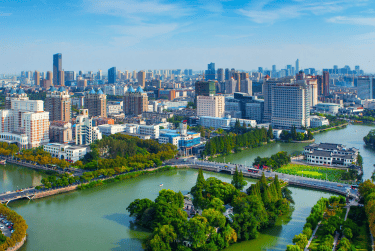 Aerial view of Nantong city skyline with skyscrapers and the Hao River under a clear blue sky.