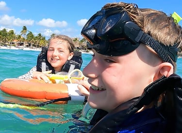 a boy and girl in wetsuits in the water