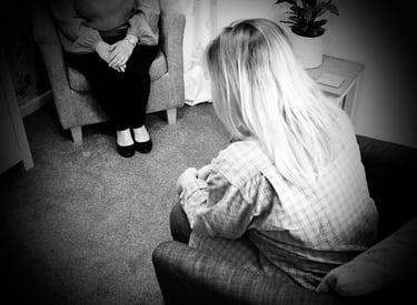 young blond haired lady with head down sat across from lady