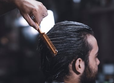 Coiffeur peignant les cheveux mouillés d’un homme vers l’arrière.