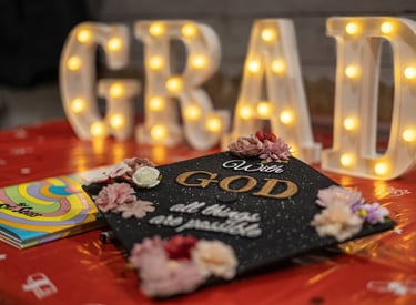 Close up image of a graduation cap with "With God all things are possible" written on the top
