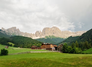 Drone photography of Cyprianerhof Dolomit Resort with the Rosengarten mountain in the background.