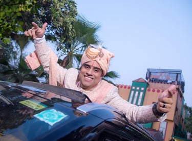 Groom in turban leaning out of a car sun roof and dancing on his wedding day..