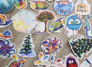 Collection of colorful watercolor stickers featuring animals, nature, and whimsical characters on a wood surface.
