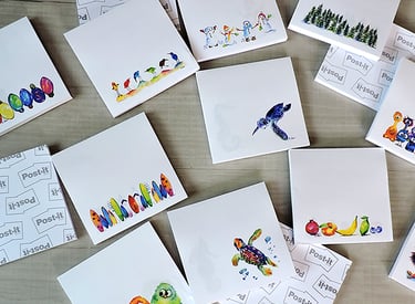Collection of decorative Post-it sticky notes with colorful watercolor illustrations on a wooden surface.