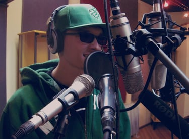 a man in a green hoodie and sunglasses is testing 6 microphones