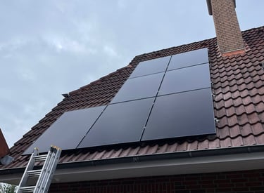 Residential rooftop solar panel installation on a tiled house with an aluminum ladder.