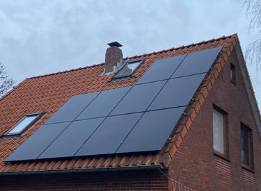 Residential rooftop solar panel installation on a red clay tile roof of a brick house.