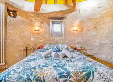 Chambre d’hôte dans un moulin rénové – lit double, serviettes pliées, murs en pierre et lumière natu