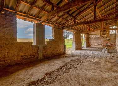 Ancienne grange en rénovation, sol décaissement et charpente visible, photo de suivi de chantier