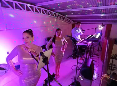 Trío Versátil Army Music actuando en un escenario iluminado en púrpura