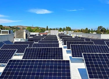 A wide commercial rooftop solar panel installation under a clear blue sky for renewable energy.