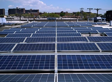 A commercial rooftop solar panel installation under a clear blue sky in an urban city environment.