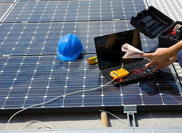 A technician performing maintenance and diagnostic testing on rooftop solar panels with a laptop.