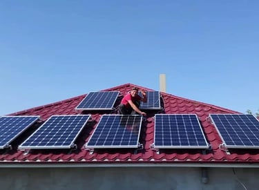 Professional technician installing solar panels on a residential red metal tile roof for renewable energy.