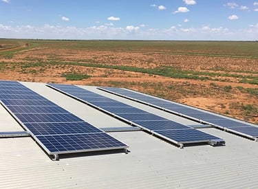 Solar panels installed on a metal roof overlooking a vast desert landscape for renewable energy.