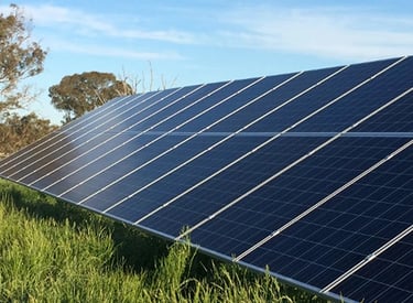 Ground-mounted solar panel array installed in a green field for renewable energy generation.