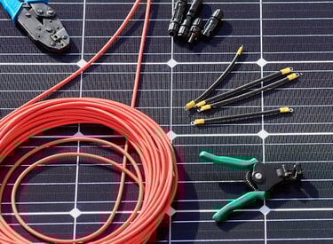 Solar panel installation tools including wire crimpers, cable strippers, and connectors on a monocrystalline solar module.