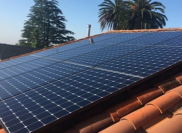 Residential rooftop solar panels on a terra cotta tile roof, generating clean energy for a home, improving energy efficiency.
