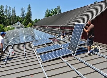 Professional contractors installing solar panels on a commercial metal roof for renewable energy.