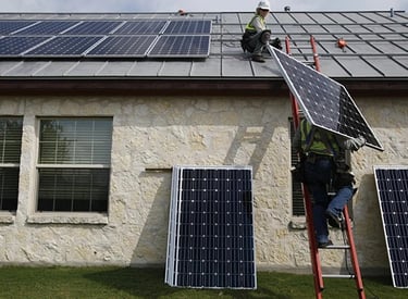 Professional solar installers mounting high-efficiency photovoltaic panels on a residential metal roof.