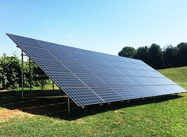 A large ground-mounted solar panel array installed on a grassy field for renewable energy.