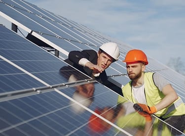 Engineers in hard hats inspecting a solar panel farm installation for renewable energy.