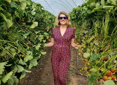 Designer and creator of clothing at Distinctly Individual woman in strawberry print jumpsuiti