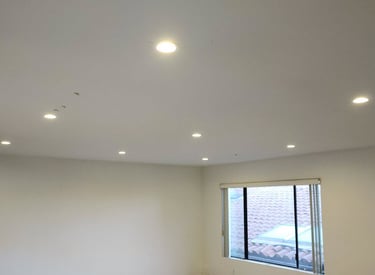 Modern white room featuring installed recessed LED ceiling lights and light wood flooring.
