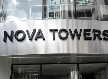 Brushed aluminium building signboard on glass tower – SignageBoard.ae