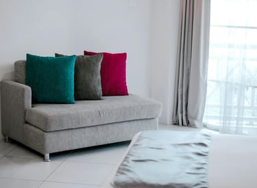 A sofa with three colored cushions on it standing in the corner of a room