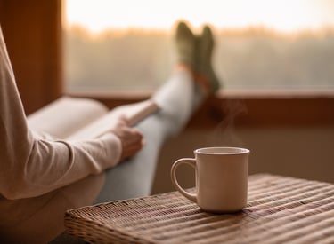 A person sitting on a chair with a cup of coffee, relaxing