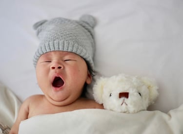 Gorgeous baby yawning with teddy ready for sleep