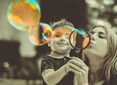 Nanny and child blowing bubbles in a park
