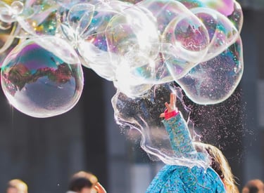 Child trying to catch giant bubbles in a playground